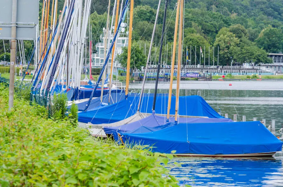 Sailboats under a blue tarpaulin cover on a berth in the harbour